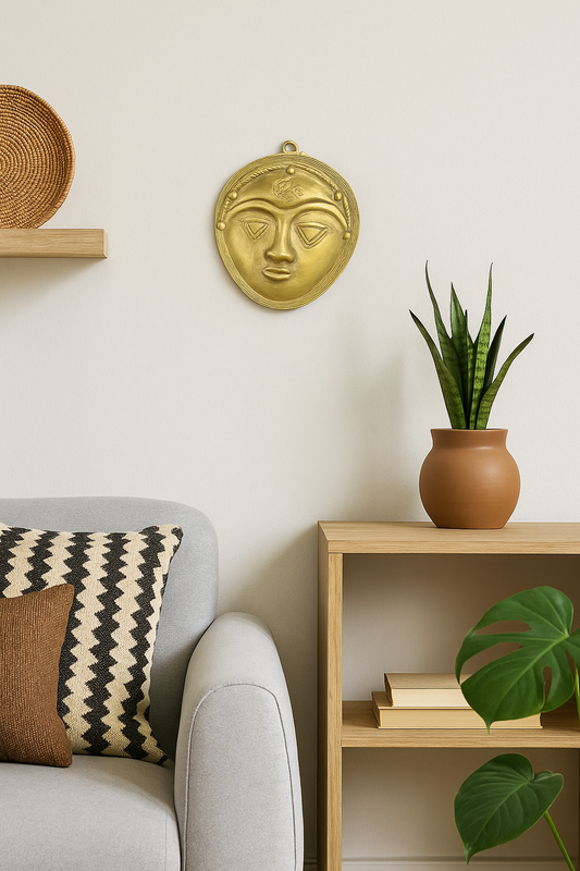 Handcrafted African brass face mask wall art displayed in a cozy modern living room with neutral decor, wooden furniture, woven accents, and green houseplants