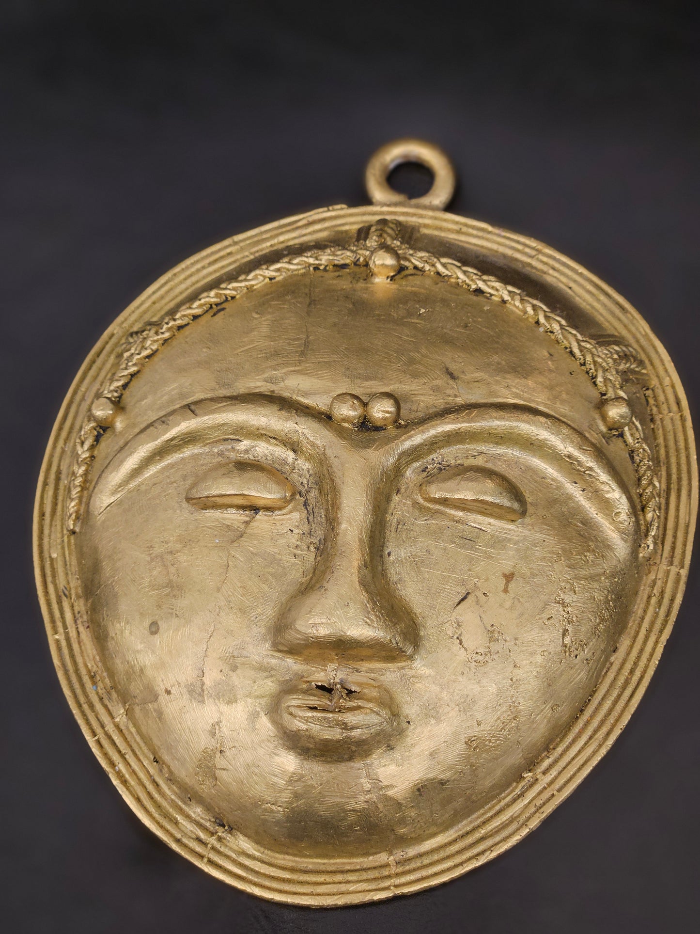 Zoomed-in view showing brass texture and craftsmanship of tribal African wall mask