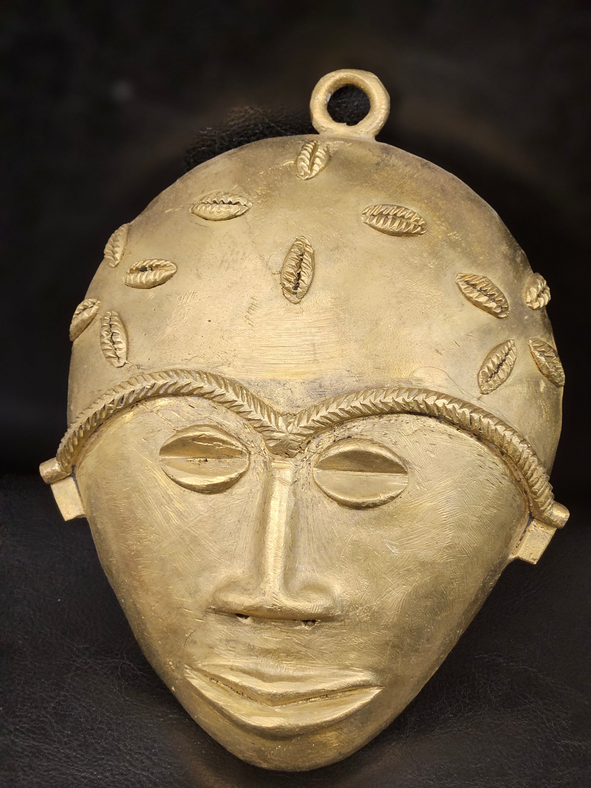 Front-facing view of a handcrafted XLarge Ashanti brass mask from Ghana, detailed with cowrie shell motifs symbolizing wealth and protection.
