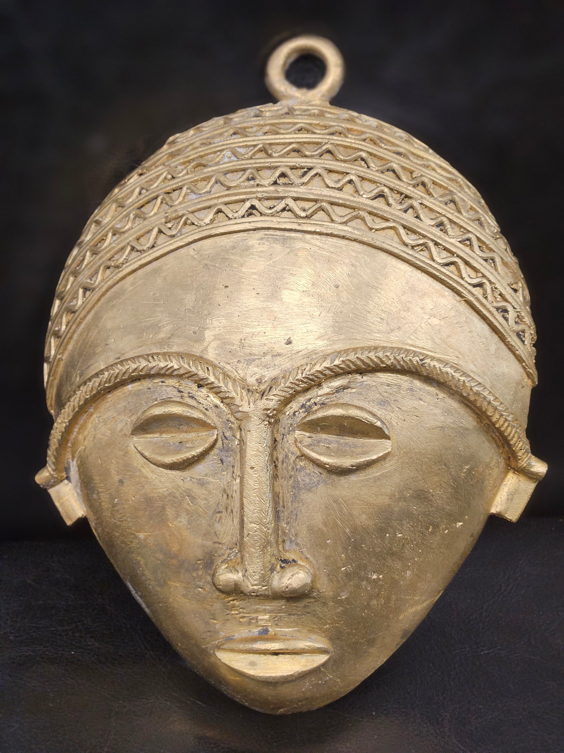 Front-facing view of authentic African brass wall mask, handcrafted in Ghana’s Ashanti Region with traditional tribal features