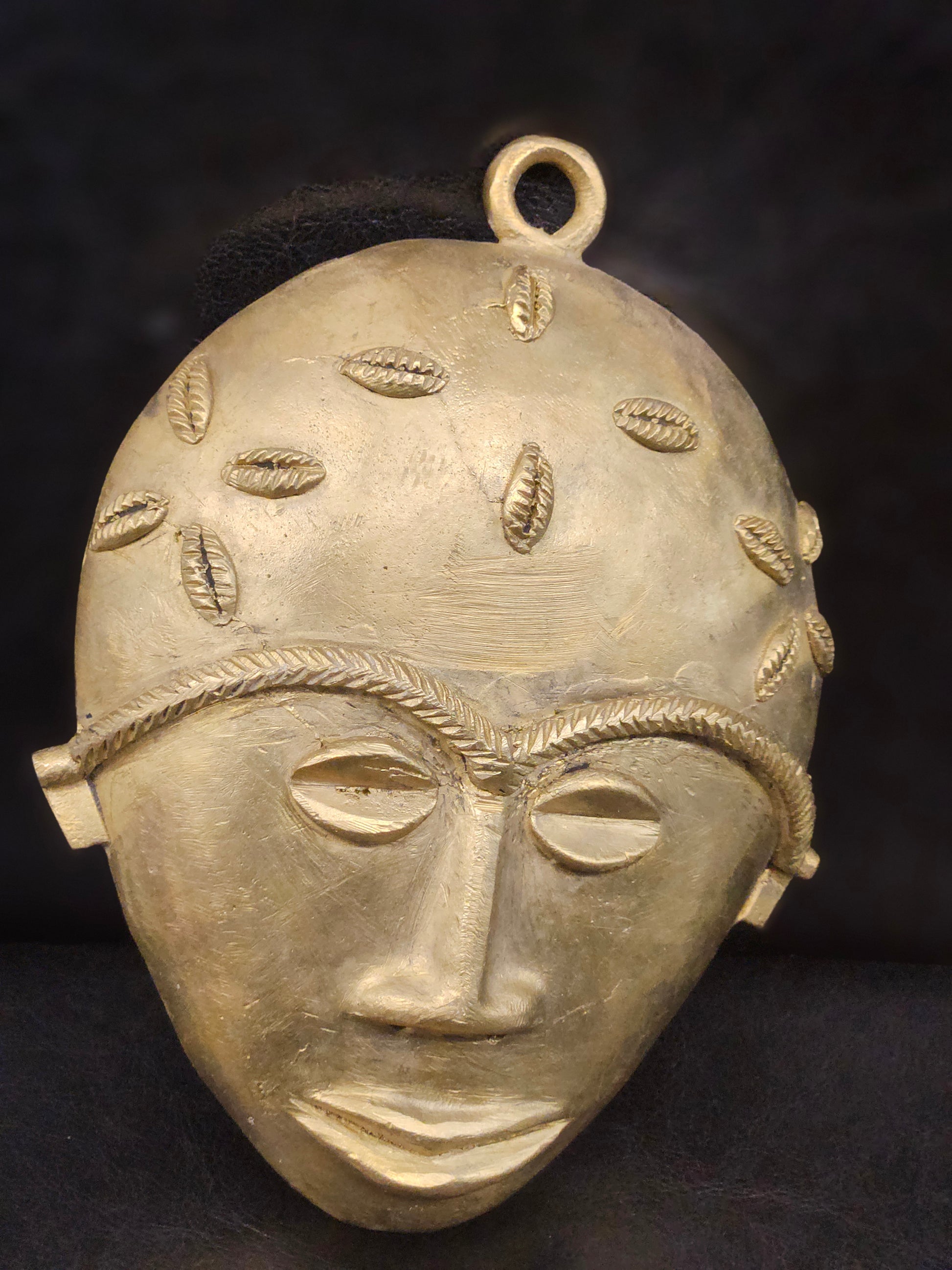 Side-angle view of the Aacheyova brass wall mask showing detailed textures and artisan craftsmanship from Ghana’s Ashanti Region.
