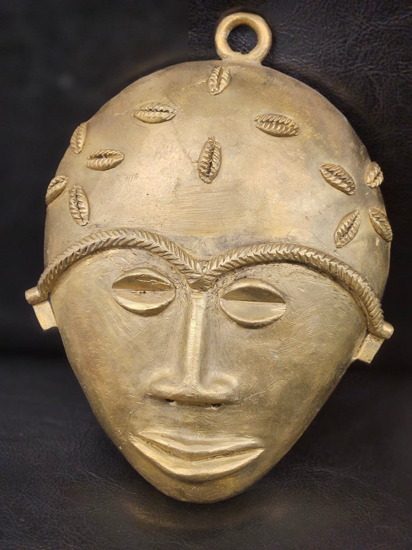 Ethically handmade Ashanti mask from Ghana, crafted in authentic brass and styled for premium Afrocentric interior design.
