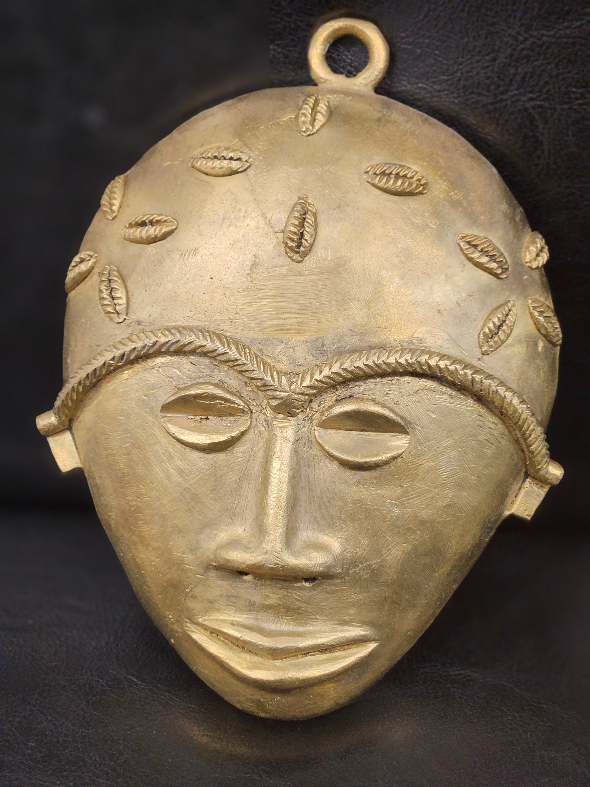 Ethically handmade Ashanti mask from Ghana, crafted in authentic brass and styled for premium Afrocentric interior design.