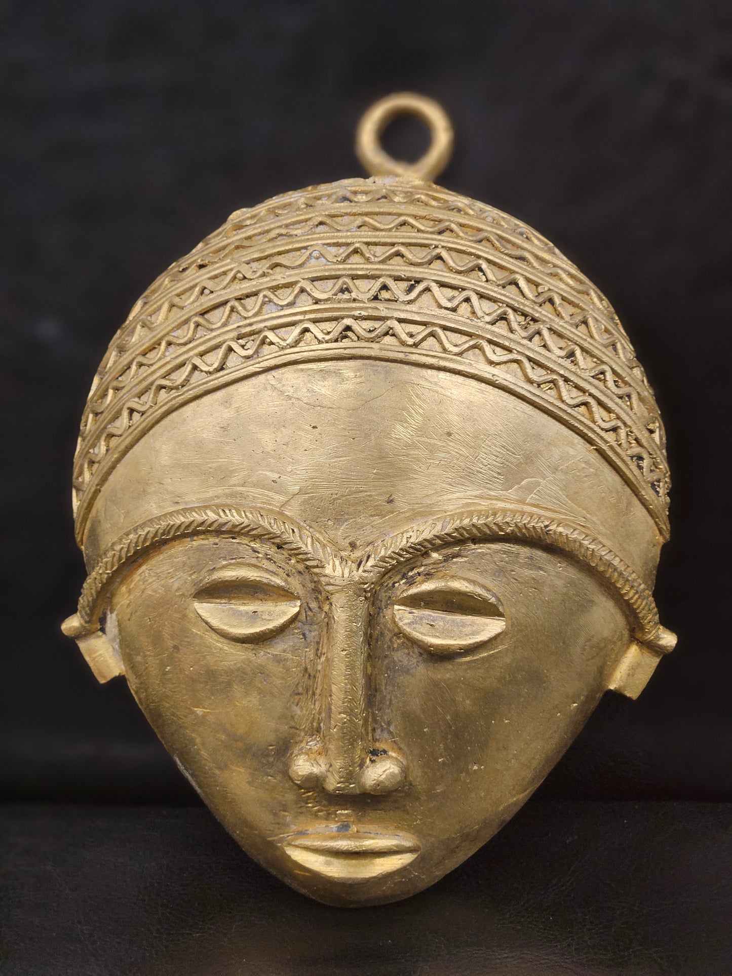 African brass wall mask displayed in facing position.