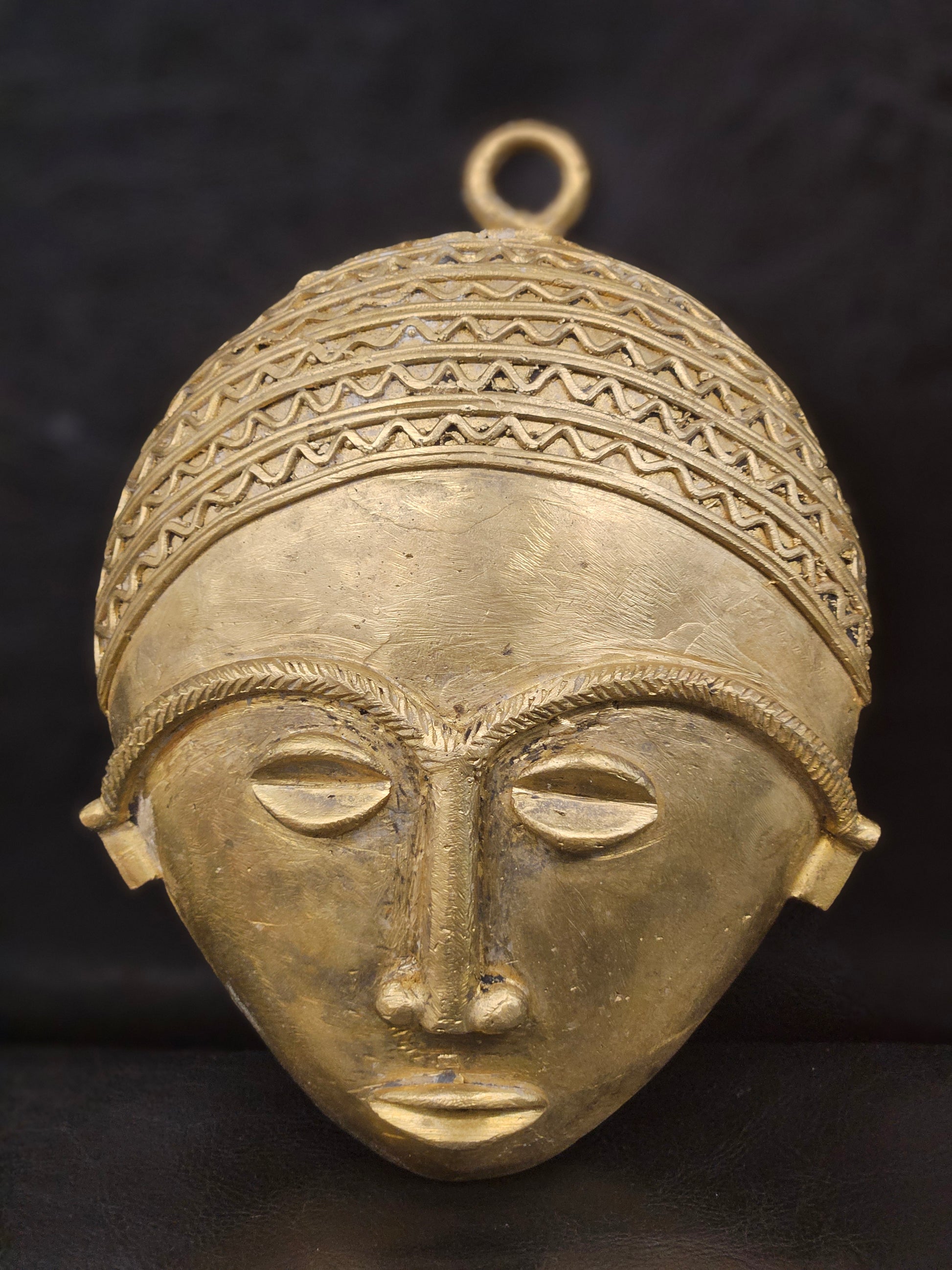 African brass wall mask displayed in facing position.