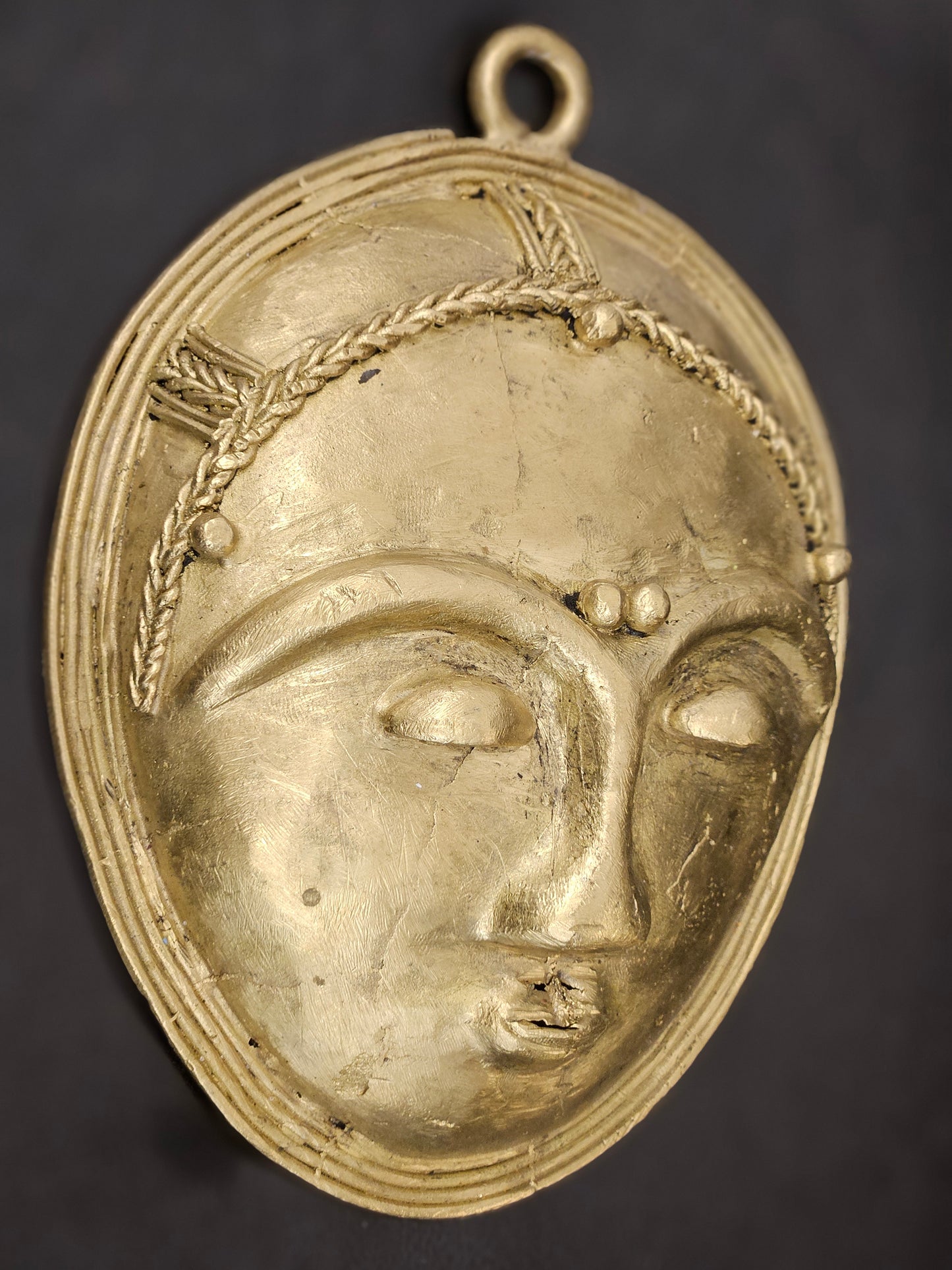 Side angle of authentic African handcrafted brass face mask, artistic tribal wall hanging